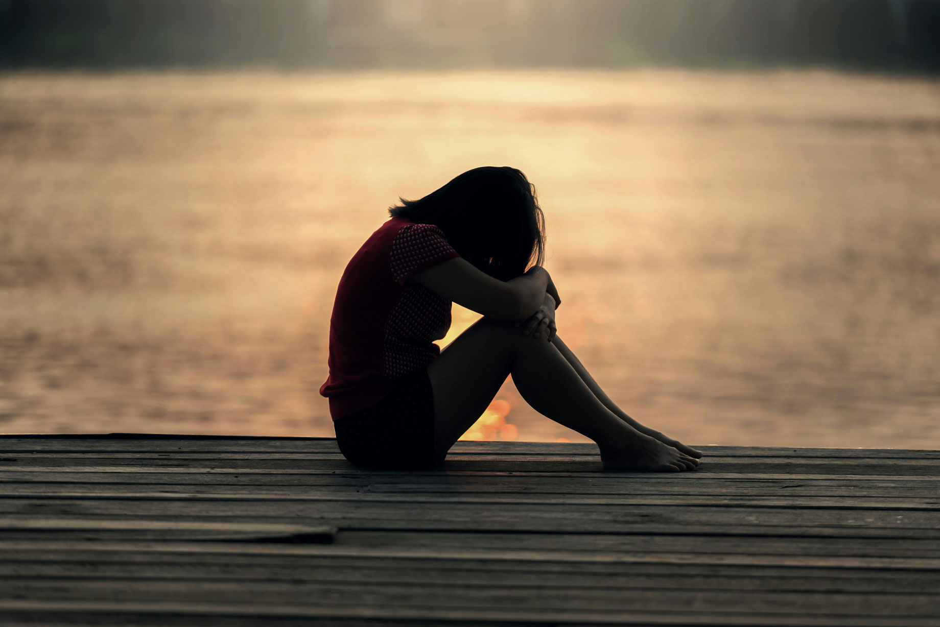 sad teen sitting by the docks